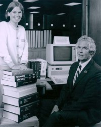 Humphreys stands behind a short stack of books while Lindberg sits in front of a computer