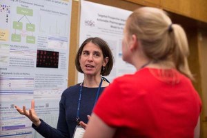 Schneider talks to a colleague in front of her research poster